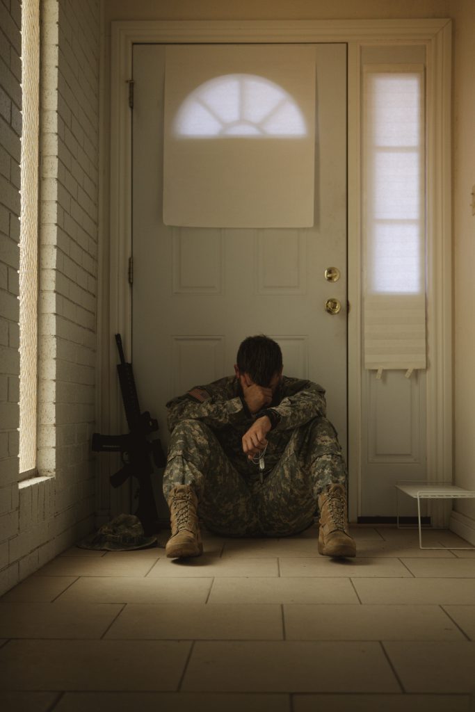 Solider crying in front of a front door to a house.